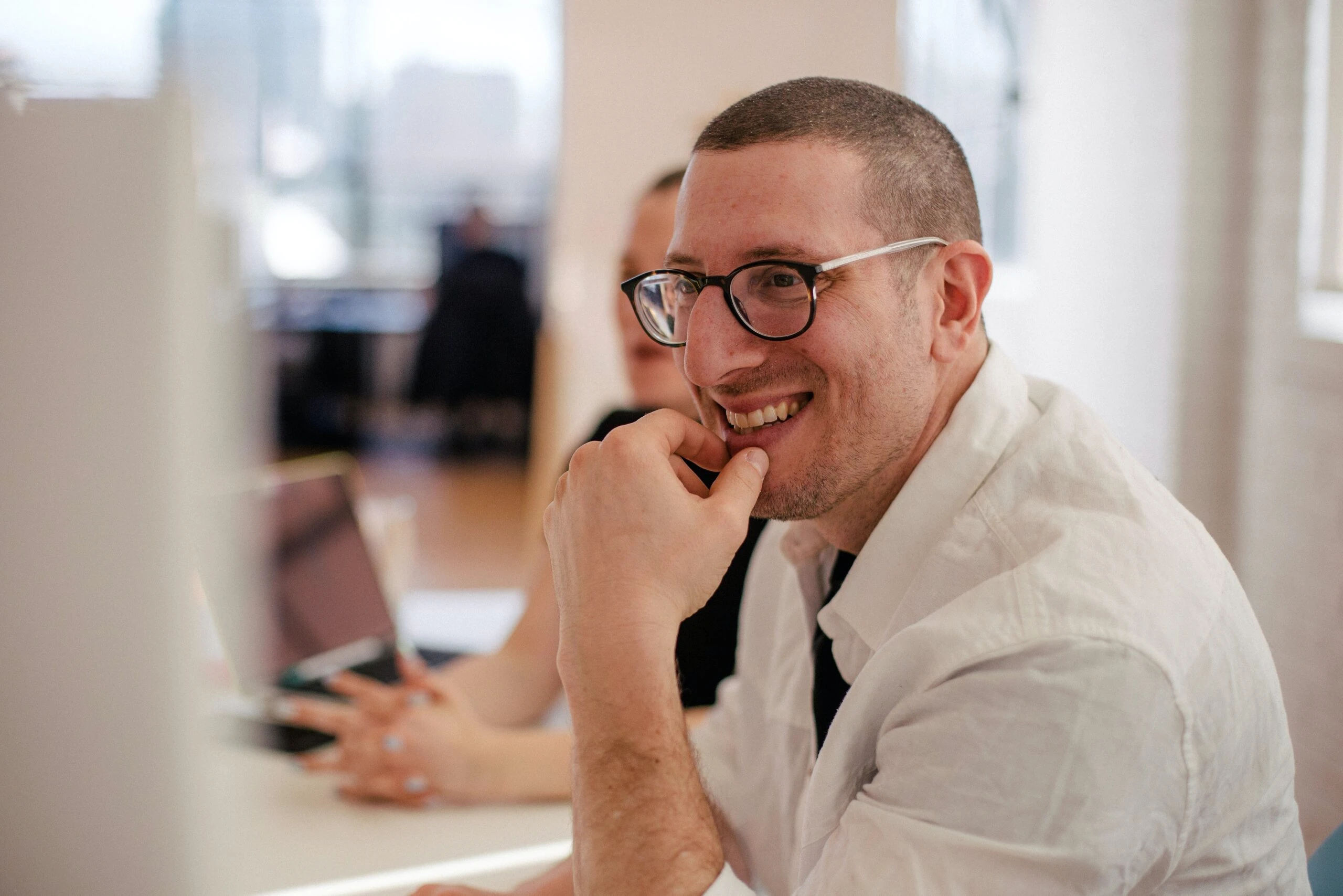 Hombre sonriente con lentes en una reunión de diseñador UX.