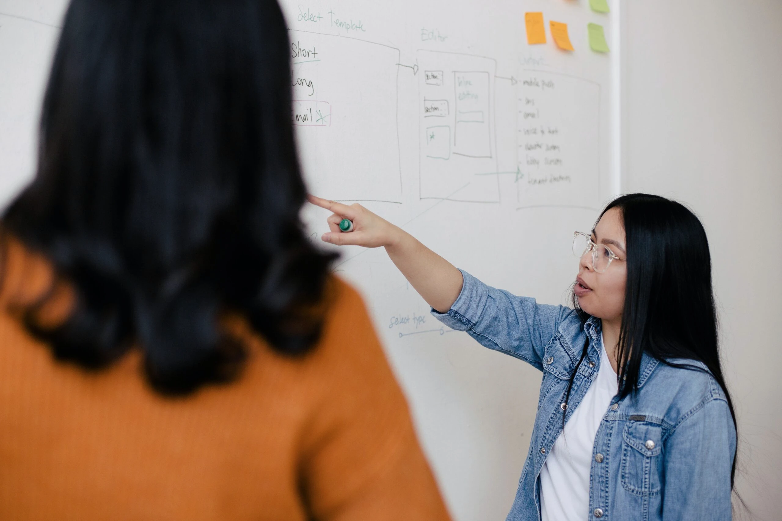 Mujer señalando a pizarra con nota, diseñadores-ux-brainstorming.