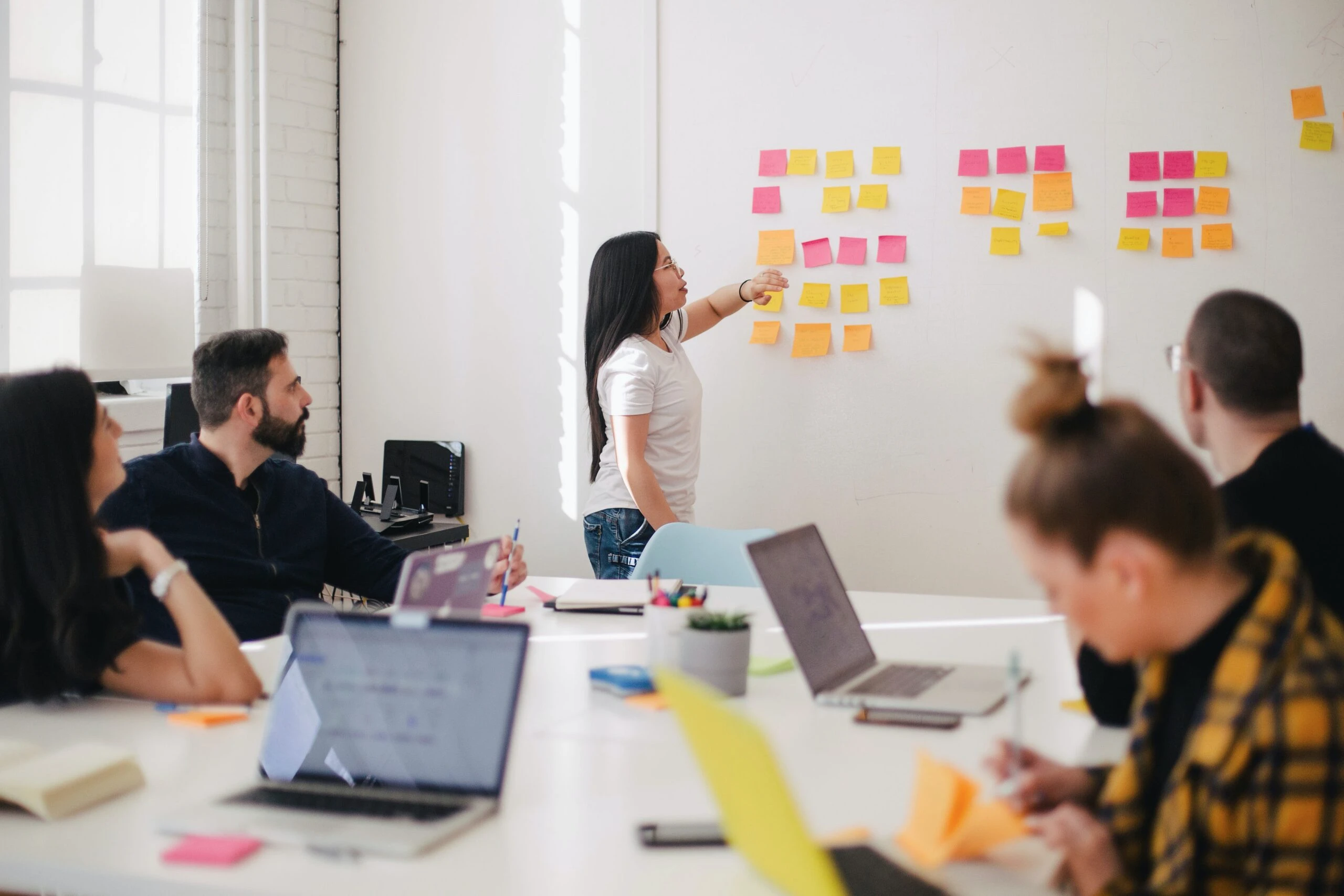 Un grupo de personas trabajando en laptops en una oficina durante una reunión de diseñadores UX.