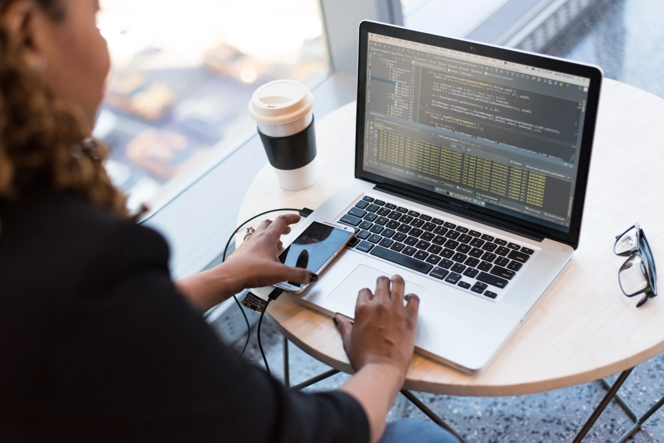 Una mujer usando su computadora portátil con una taza de café mientras realiza pruebas de aplicación para UX.